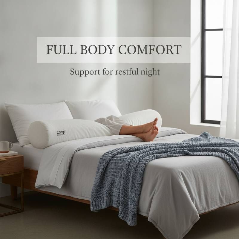 A Coop Sleep Goods body pillow lying on a bed