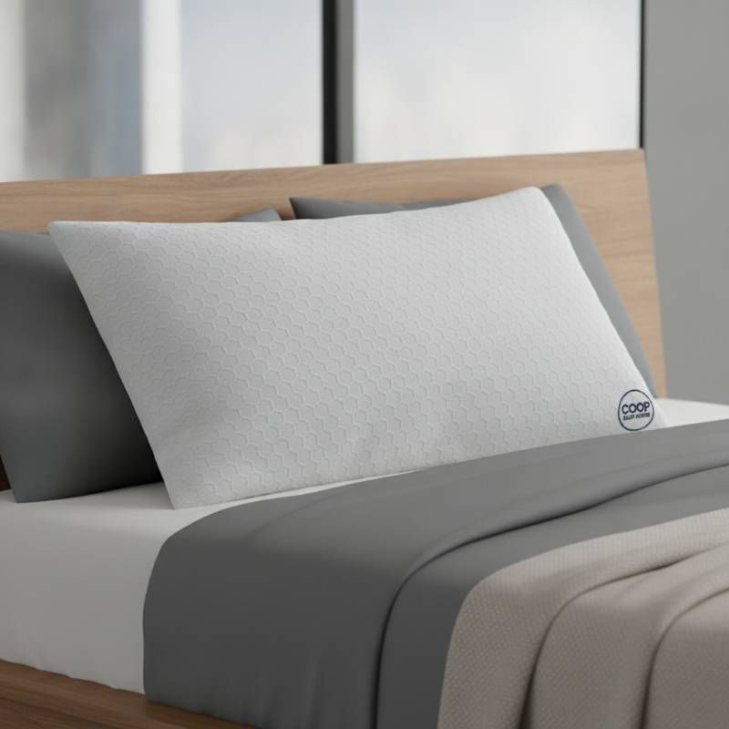 The Coop Sleep Goods Original Adjustable Pillow lying on a bed with its bamboo-derived cover visible